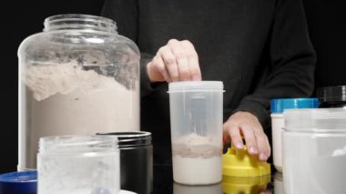 Sporcu, protein tozunun daha iyi karıştırılması için karıştırıcı şişeye bir ızgara yerleştiriyor ve sonra da kapağı güvenli bir şekilde kapatıyor. Yavaş çekim.