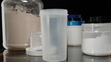 Protein tozu boş bir karıştırıcı şişeye boşaltılıyor, bir sonraki egzersiz sonrası ilave karışımı için hazırlanıyor. Yavaş çekim.