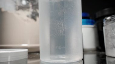 Protein tozunun yakınlaştırılmış hali bir karıştırıcı şişenin dibine yerleşiyor ve tabanı protein içeceği için hazırlıyor. Yavaş çekim.