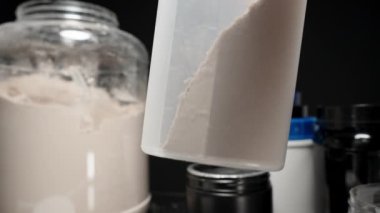 Titreşim şişesinin içindeki protein tozu miktarını ölçmek dengeli bir sallantı için doğru dozajı sağlıyor. Yavaş çekim.