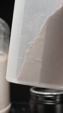 Dikey video. Titreşim şişesinin içindeki protein tozu miktarını ölçmek dengeli bir sallantı için doğru dozajı sağlıyor. Yavaş çekim.