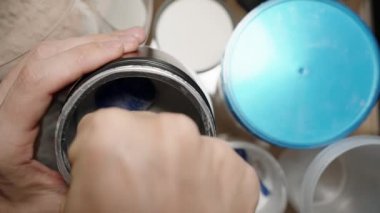 Sporcu, BCAA tozunu ölçmek için mavi kepçe kullanarak kas iyileşmesi ve dayanıklılığını garantiliyor. Yavaş çekim.