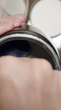 Dikey video. Sporcu, BCAA tozunu ölçmek için mavi kepçe kullanarak kas iyileşmesi ve dayanıklılığını garantiliyor. Yavaş çekim.