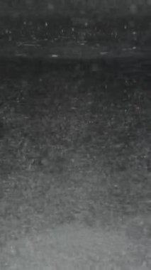 Dikey video. Bir bardak suda dönen çözülmemiş toz parçacıkları yavaşça karışıyor ve yerleşiyor..