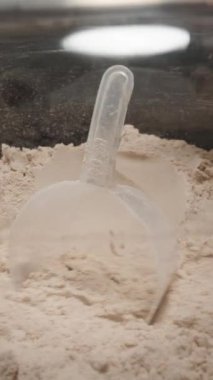 Dikey video. Konteynırdan bol miktarda Protein tozu alıp kullanım ya da depolama için hazırlanıyor..