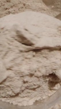 Dikey video. Fazla protein tozunu kaşıktan konteynıra atıp fazlalığı ortadan kaldırıyor..