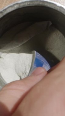 Dikey video. Antrenman öncesi pudra kavanozuna mavi bir kepçeyle uzanarak servis atışını ölçmeye hazırlanıyor. Dolly Slider, kapat. Yavaş çekim.