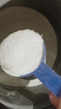 Dikey video. Barutun bir kısmını ölçüp kesin miktarı alabilmek için fazlalıkları silkeleyeceğiz. Yavaş çekim.