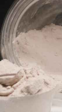 Dikey video. Dolly sürgüsü, Protein tozu havaya dağılırken yakın çekim için harekete geçiyor. Dolly kaydırıcı, kapat..