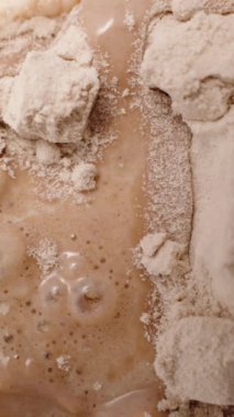 Dikey video. Titretici şişeyi protein tozu ve sütle sallayarak pürüzsüz ve hatta karışık olmasını sağlıyorlar..