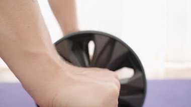 Mor yoga minderinin üzerinde bir ileri bir geri yuvarlanan Ab silindiri, yoğun bir egzersiz sırasında çekirdek kaslarını çalıştırır.
