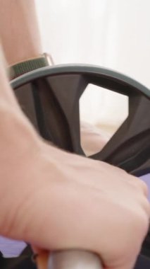 Dikey video. Eller Ab Roller 'da sabit, mor bir paspas üzerinde yuvarlanıyor, üst gövde ve çekirdek gücünü arttırıyor..