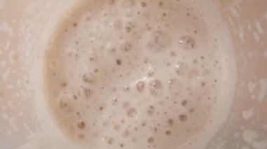 Protein Shake köpüğünde kabarcıkların kabarcıklarının patlaması içkinin zenginliğini ve tutarlılığını vurguluyor..