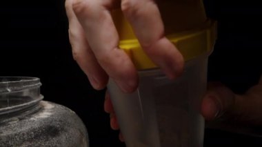 Bir el, Sarı Lid 'i Shaker Kupası' na yatırır ve içindekileri sallamak ve karıştırmak için sıkı bir şekilde hazırlar..