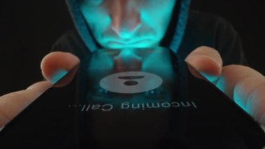 Bilinmeyen Numara 'yı gösteren bir telefon ekranının üzerinde gezinen ve bilinmeyen bir çağrıya cevap vermeden önce tereddüt eden bir kişinin yakın plan görüntüsü. Dolly kaydırıcı, kapat..