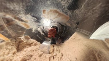 Yakınlaştırın, bir Protein Toz kavanozunun içinden bakın, bir adam ölçüm kabıyla tozu kepçeler. Karanlık ortam, kabın içindeki toz dokusunu vurguluyor..