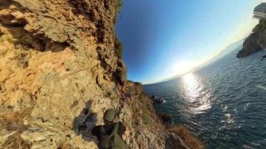 Okyanusa bakan bir uçurumun kenarındaki küçük bir mağarada dinlenen iki kişi küresel bir panorama içinde yakalandı..