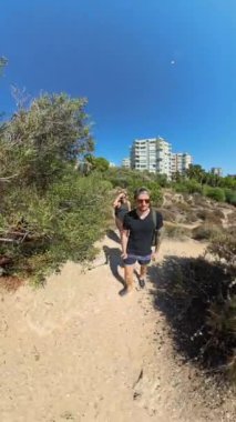 Dikey video. Berrak mavi suları ve uzak dağlarıyla kayalık bir kıyı şeridinin panoramik manzarası denizin ve manzaranın enginliğini ve güzelliğini gözler önüne seriyor..