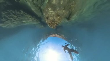 360. Delik Gezegeni sualtı görüntüsü mağara benzeri bir tünelden yükselen bir şnorkelci, yukarıdan gelen güneş ışığıyla dramatik ve daldırıcı bir sualtı sahnesi yaratıyor..
