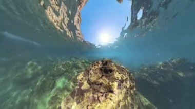 Daha küçük oluşumlarla çevrili, 360 derecelik bir panorama. Güneş ışığı yukarıdan içeri girerek sualtı manzarasının renklerini ve dokularını güçlendiriyor..