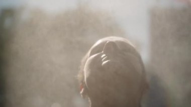 Yüzü yukarıya doğru eğilmiş, etrafı sis ve güneş ışığıyla çevrili, dingin ve manevi bir etki yaratan bir kadın. Düşük açı ve hafif ışıklandırma bir huzur ve rahatlama anını vurguluyor..