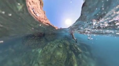 360. Gezegen Deliği küresel panorama dalgıcı aşağıdaki kayalık araziyle su yüzeyine yaklaşıyor. Düşük açılı sualtı görüntüsünden geniş açılı çekim.