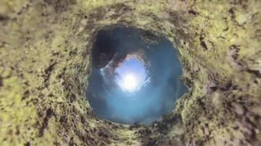 Delik Gezegeni batık bir mağaranın içinden yukarıya bakıyor. Güneş ışığı yukarıdaki dairesel bir delikten içeri giriyor. Küresel panorama etkisi.