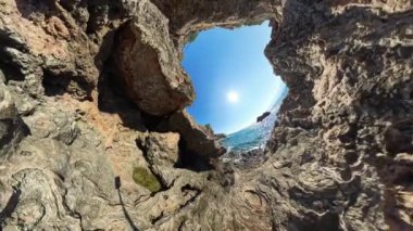 360 derece kamera. Güneşe doğru bakan iki kayalık uçurum arasından bir manzara. Güneş ışığı engebeli araziden yansıyarak doğal manzarayı aydınlatıyor. Sahnenin geniş açılı görüntüsü..