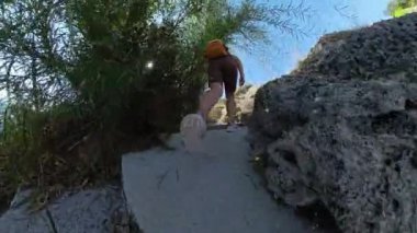 Stone Steps 'e tırmanan bir kadının alçak açılı görüntüsü. Güneş tepede parlıyor. Sırt çantası ve çevre yeşillik Geniş Açı perspektifi tarafından vurgulanır.