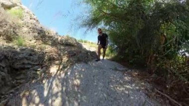 Bir adamın mavi demiryolu ile Stone Steps 'e tırmanırken geniş açılı görüntüsü. Okyanus, parlak bir güneşin altında uzanırken engebeli kıyı arazisini yakalıyor..