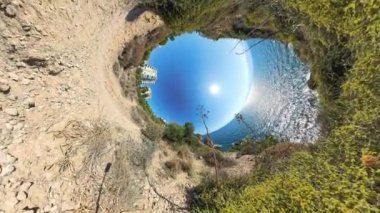 Bir kıyı manzarasının 360. Delik etkisi. Yol ve çevresindeki bitki örtüsü eğrisi merkezde okyanus ve güneş olan dairesel bir manzara yaratıyor..