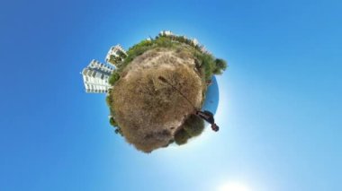 Küçük Gezegen 360 efekti, bir adamın Rocky Arazisinde durduğunu, çevresindeki bitki örtüsüyle okyanus ve binaların, açık mavi gökyüzü altında küre ufkunun etrafında kıvrıldığını gösteriyor..