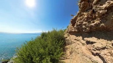 Okyanus ufka kadar uzanan Rocky Coastal Trail 'in manzarası. Güneş suyun üzerinde ışıl ışıl parlarken yemyeşil yol kenarlarını kaplıyor..