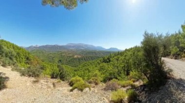 Bir kadın uçurumun kenarında yürüyor, geniş açılı, bir çubuğun üzerinde 360 derecelik kamerayla yakalanmış. Çekim, dik düşüşü ve geniş doğal çevreyi vurguluyor..