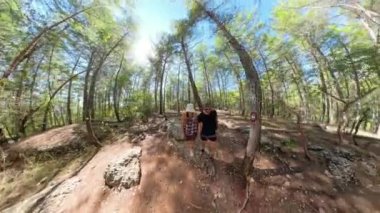 Bir süper geniş açı çekimi ağaçlar orman yolunda yürüyen adam ve kadının etrafındaki kıvrımları bozuyor. Gerçeküstü etki, etrafını saran ormanın dairesel ve sürükleyici bir görüntüsünü yaratıyor..