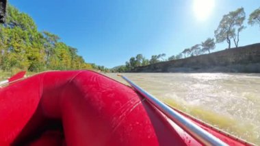Sakin bir nehirde kürek çeken kirişlerin yakın plan görüntüsü, nehirden yansıyan güneş ışığı ve nehir kıyısındaki ağaçlar, huzur verici bir manzara yaratıyor..