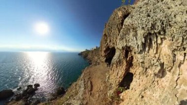 360 derece dönüş. Geniş Açı, engebeli bir sahil uçurumu, denizin altında uzandığı bir yol. Güneş ışıl ışıl parlıyor, kayalık oluşumlara ışık tutuyor ve dramatik ve maceralı bir kıyı yolu oluşturuyor..