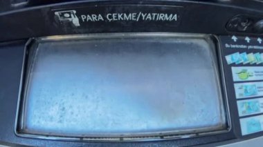 ATM 'den para çeken bir elin yakın plan çekimi, birinci şahıs perspektifi sağlıyor, para transferi sırasında makineyle etkileşime odaklanıyor.