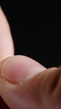 Dikey video. Sigarayı bırakma kavramı, bir adamın sigarayı parmaklarının arasında kırması, tütünün dökülmesi, kötü alışkanlığı sembolize eden siyah bir arka plan..
