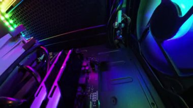 Geniş açılı bir kamera, bir oyun bilgisayarının iç görüntülerini yakına çeker, RGB ışıkları, soğutma vantilatörleri ve yüksek teknolojili donanım bileşenlerini göstermek için farklı yönlere hareket eder..