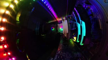 Canlı RGB aydınlatma ve soğutma vantilatörleri olan oyun bilgisayarının içinden bir görüntü, cam paneli bir bezle silen bir adamı gösteriyor. Renkli bileşenler ve donanım aydınlatılıyor ve yüksek teknolojili bir atmosfer yaratıyor..