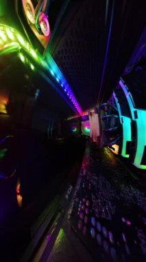 Dikey video. Canlı RGB aydınlatma ve soğutma vantilatörleri olan oyun bilgisayarının içinden bir görüntü, cam paneli bir bezle silen bir adamı gösteriyor. Renkli bileşenler ve donanım aydınlatılıyor ve yüksek teknolojili bir atmosfer yaratıyor..