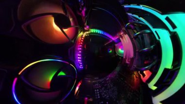 Bir oyun bilgisayarının içinden dönen panoramik bir görüntü, canlı RGB ışıkları, soğutma vantilatörleri ve donanım bileşenlerini gösteren bir adam cam paneli kumaşla silerken. Dinamik çekim, aydınlatılmış teknik tertibatı vurguluyor..