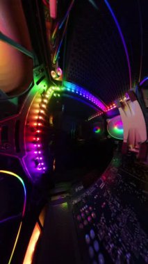 Dikey video. Bir oyun bilgisayarının içinden dönen panoramik bir görüntü, canlı RGB ışıkları, soğutma vantilatörleri ve donanım bileşenlerini gösteren bir adam cam paneli kumaşla silerken. Dinamik çekim, aydınlatılmış teknik tertibatı vurguluyor..