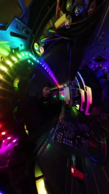 Dikey video. Bir adam, bir oyun bilgisayarının cam yan panelini ve içerideki akranlarını kaldırıyor, yakın çekim, geniş açı görüntüsü var. Sahne canlı RGB ışıklandırma ve donanım bileşenleri vurguluyor yüksek teknoloji, aydınlatma.