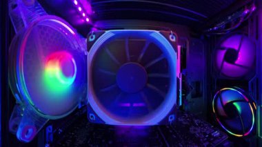 Bir oyun bilgisayarının içinde, canlı RGB aydınlatma ve soğutma vantilatörleri gösteren sabit bir yakın çekim. Aydınlatılmış donanım bileşenleri yüksek teknolojili, statik çerçevede parlayan yapıyı vurgulayarak ayrıntılı olarak görüntülenir.