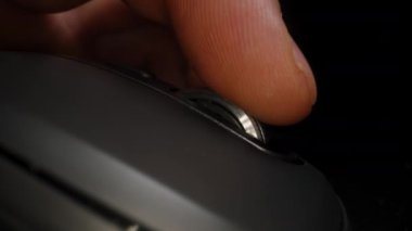 Yavaş çekimde, faredeki manyetik parşömen düzgün döner. Pürüzsüz bir bilgisayar faresinde metal bir parşömen tekeri kullanan bir elin yakın çekimi, dokulu tekerleği ve minimalist tasarımı vurguluyor, düşük açılı, odaklı bir perspektif.