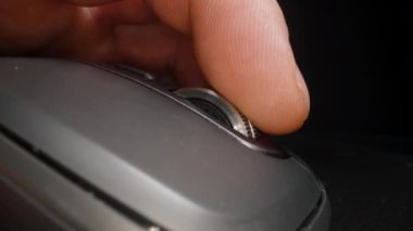 Düz bir bilgisayar faresinde çarkı kaydıran parmağın yakın çekimi, dokunsal kontrol ve ergonomik tasarımı detaylı, odaklanmış bir çekimde gösterir..