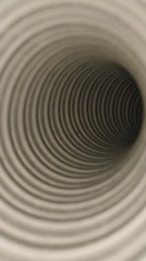 Dikey video. Yinelenen spiral desenli sarmal bir tüpü yakın çekim görüntüsü tünel benzeri bir etki yaratır. Yumuşak ve nötr bir tonda derinlik ve simetriyi vurgular..