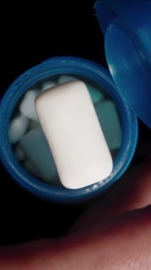 Dikey video. Tek bir beyaz sakız tableti gibi açık kapaklı mavi bir kabın genel görünümü yavaş çekimde düşerken, yakın çekim sahnesinde tazelik ve dinamik hareketi vurguluyor..